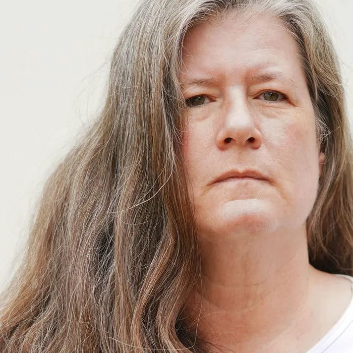 "Sad-looking older woman with grey unkempt hair"