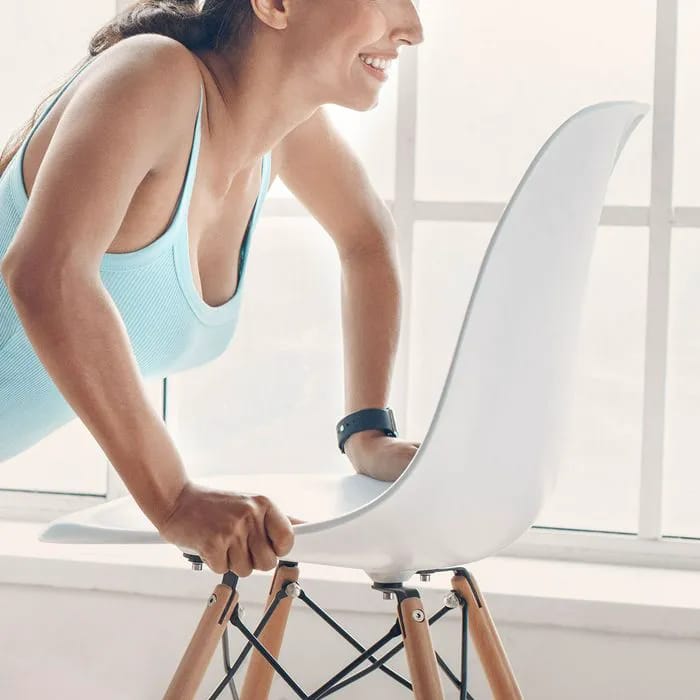 Woman exercising using a chair for support.