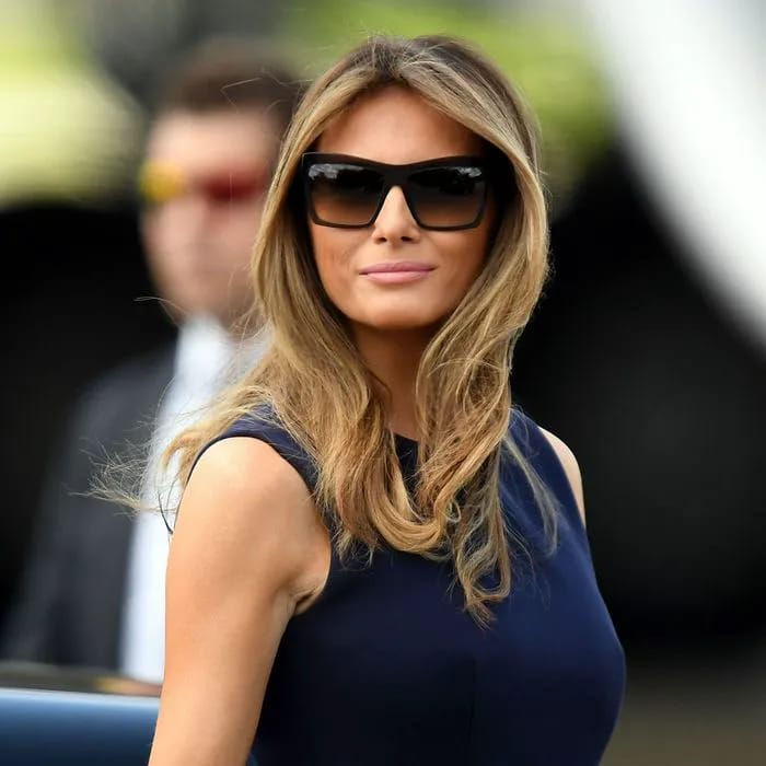 Melania Trump wearing sunglasses and a blue dress