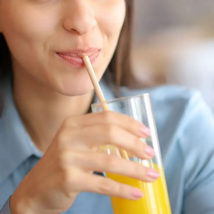 Woman drinking juice through a colorful straw.