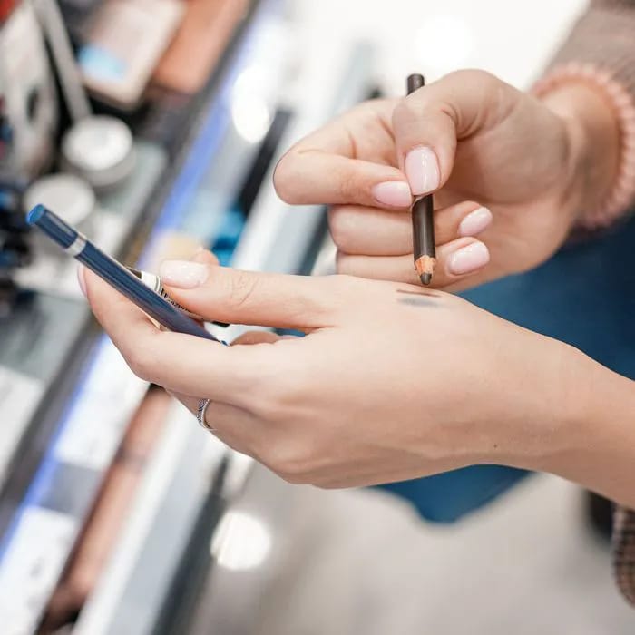 "Woman testing eyeliner pencils in a store"