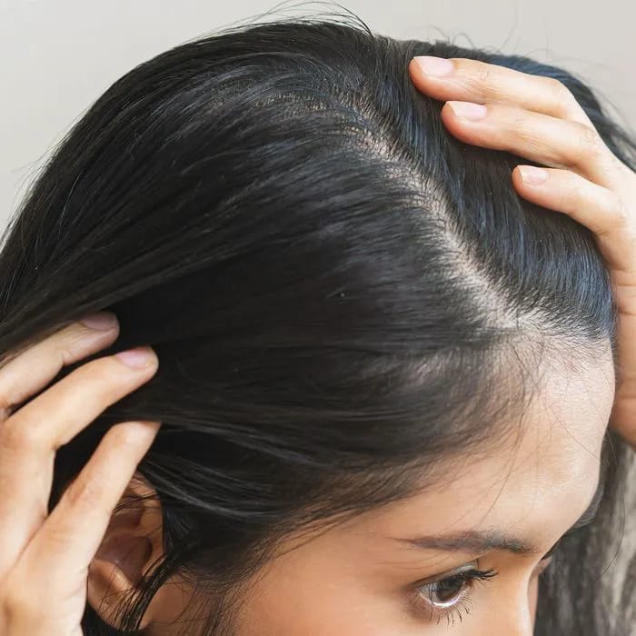 Woman examining her scalp for signs of bald spots.