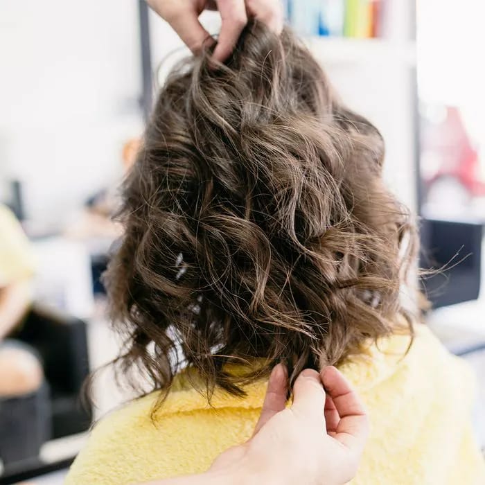 "Woman getting her hair styled at a salon with professional assistance"