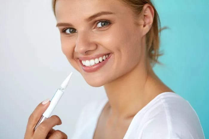 Woman applying teeth whitening gel at home