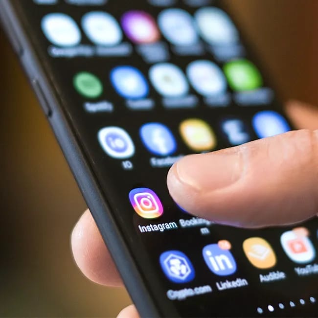 Person tapping on Instagram app using a smartphone.