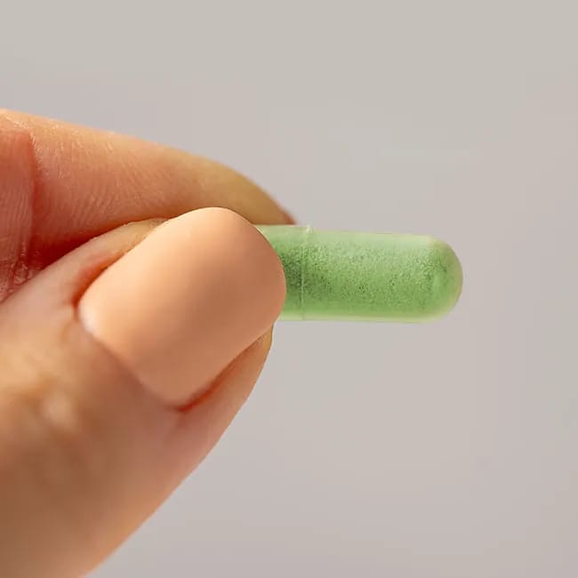 Woman showcasing a green tea supplement pill.