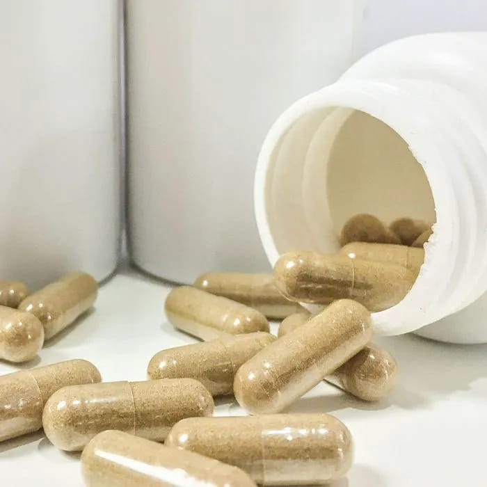 Supplement capsules spilling from a jar.
