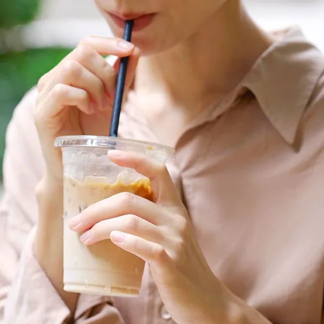 Woman enjoying an iced latte in a cafe setting.