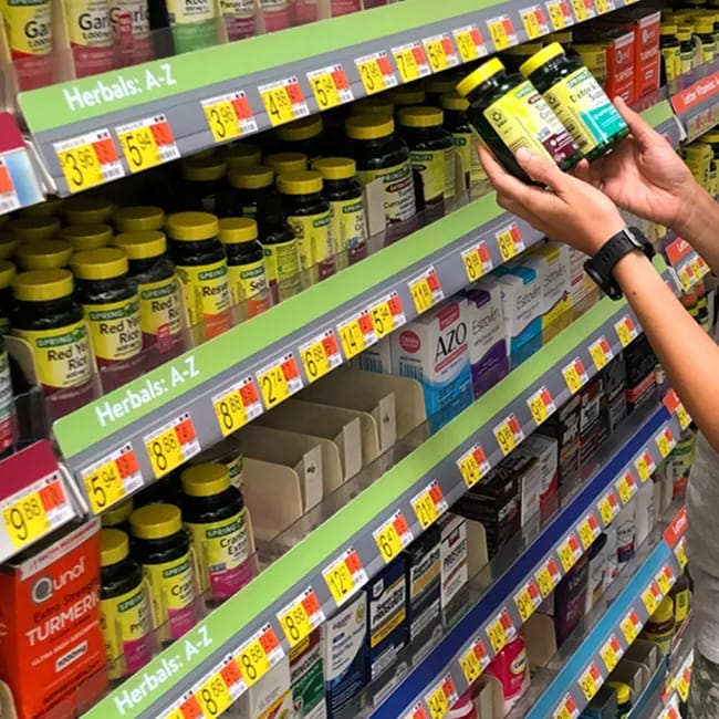 "Woman holding vitamins in the store aisle"