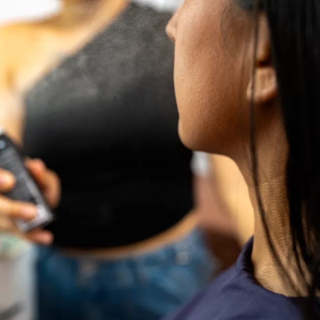 Girl applying setting spray to enhance makeup longevity.