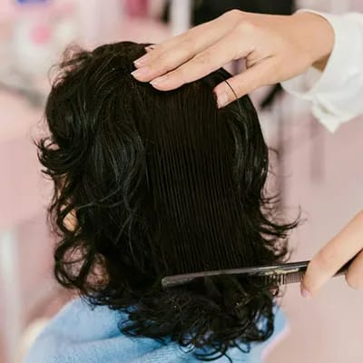 "Back view of a woman's wavy brunette shoulder-length hair"