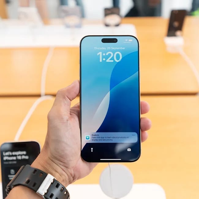Person holding an iPhone, showcasing its features.