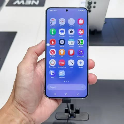 Individual holding Android phone showing various apps.
