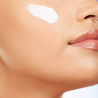 Woman applying moisturizer to her cheek for hydration.