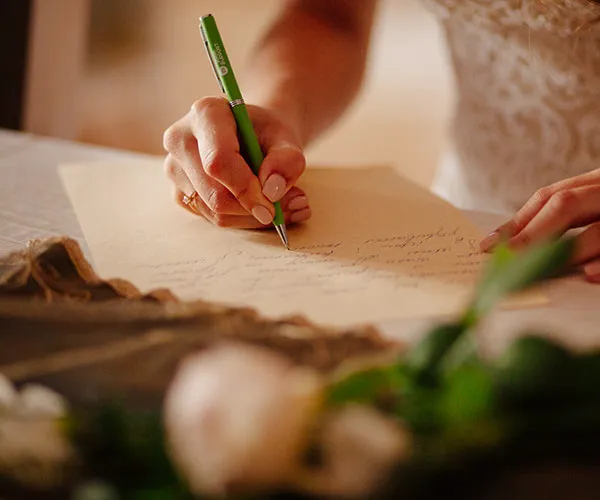 Bride writing heartfelt wedding vows on a table.
