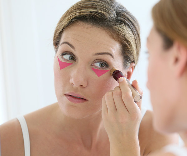 woman applying concealer to under-eyes