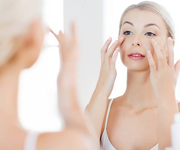 woman using skincare product in mirror