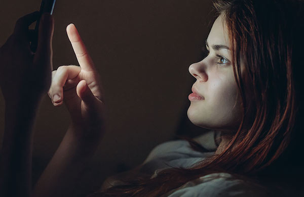 woman using phone in bed