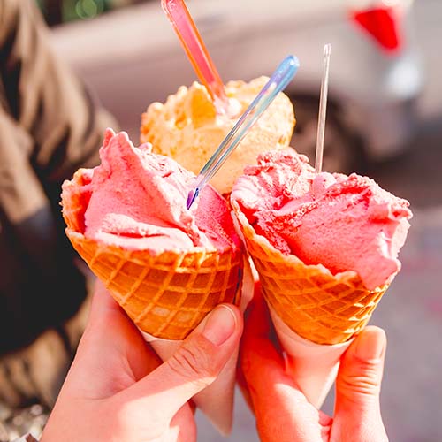 people holding strawberry ice cream cones