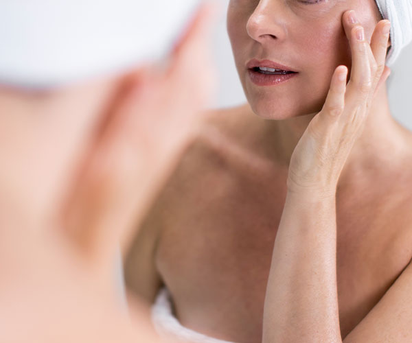woman applying skincare products in the mirror