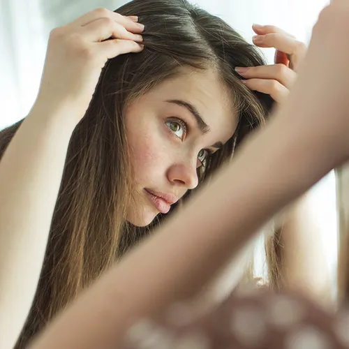 woman styling hair in mirror