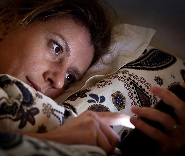 woman using phone in bed