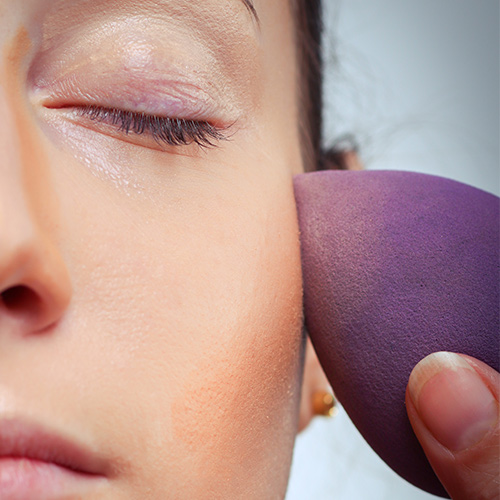 woman applying foundation with a purple beautyblender