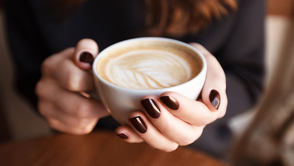 woman holding latte with latte art