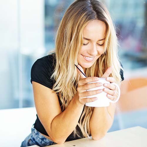 woman leaning on counter drinking coffee out of mug