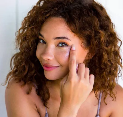 woman applying the kopari starry eye balm to her under-eyes