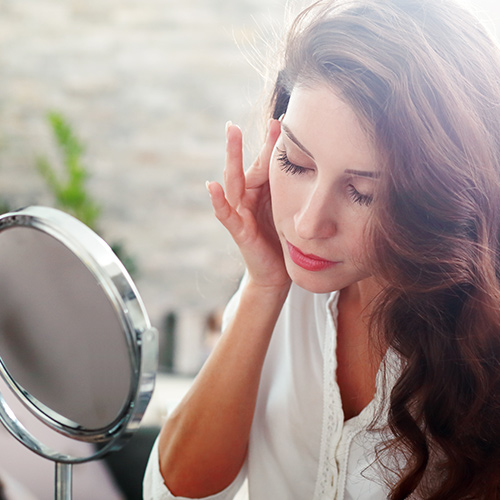 woman applying serum in mirror