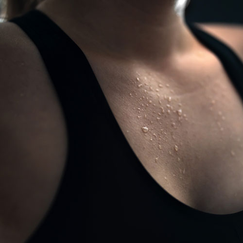 A woman with sweat on her neck and chest.