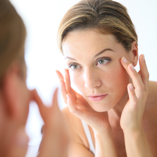 woman touching skin around her eyes