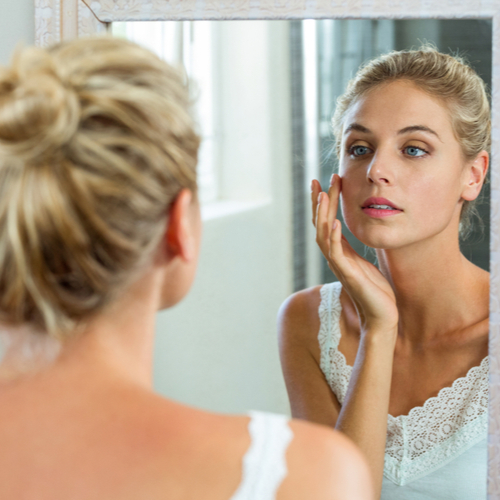 woman checking her face in mirror