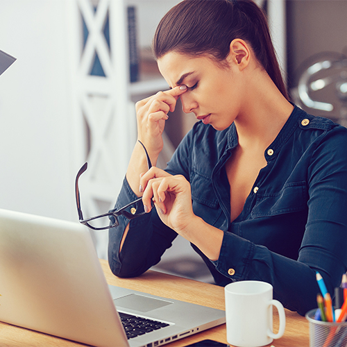A tired woman sitting at a desk.