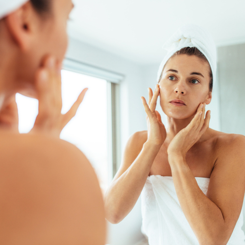 woman touching face in mirror