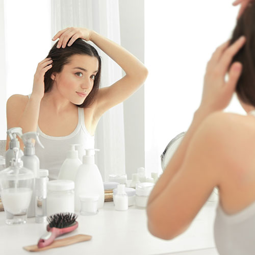 woman checking hair in mirror