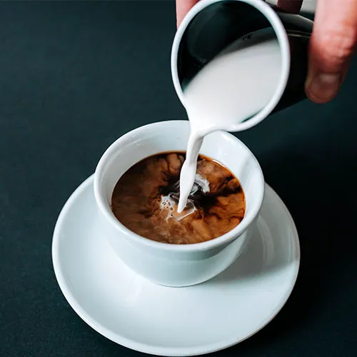 pouring creamer into coffee