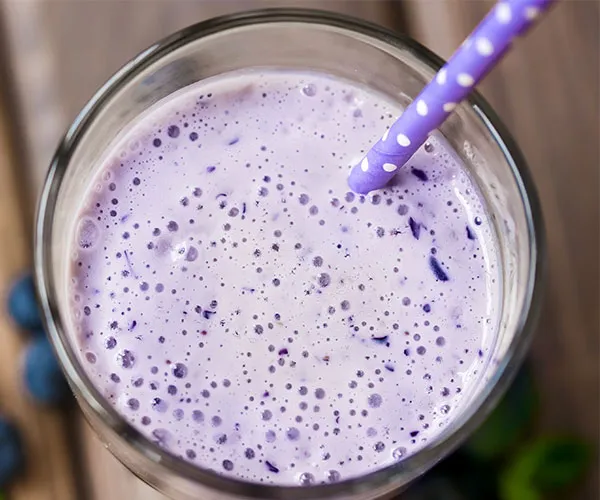 Vibrant purple smoothie with berries in a glass.
