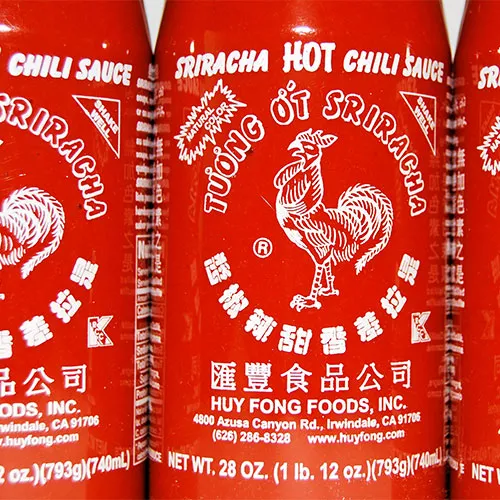 Bottles of sriracha sauce on a wooden table.
