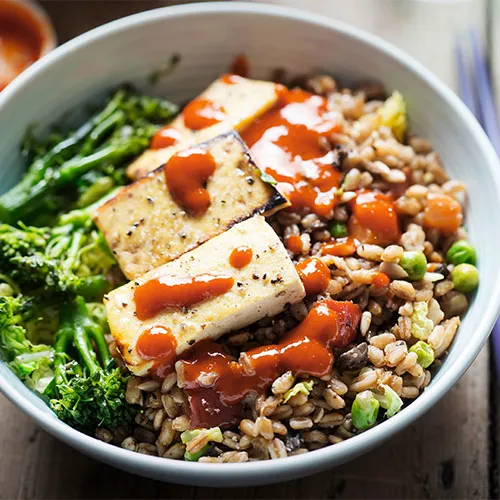 Sriracha sauce served in a stylish bowl with garnishes.