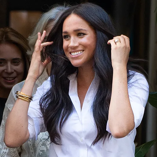 Meghan Markle posing confidently in a stylish outfit.
