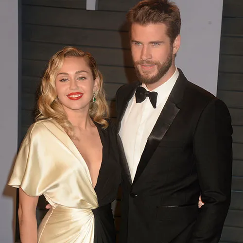 Miley Cyrus and Liam Hemsworth smiling together at an event