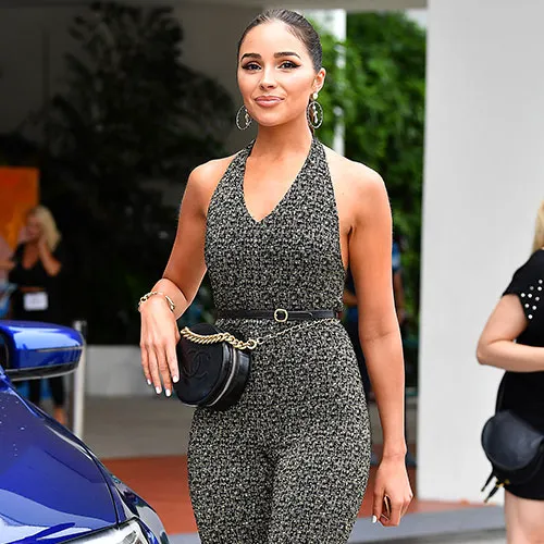 Olivia Culpo smiling in a trendy outfit on the red carpet.