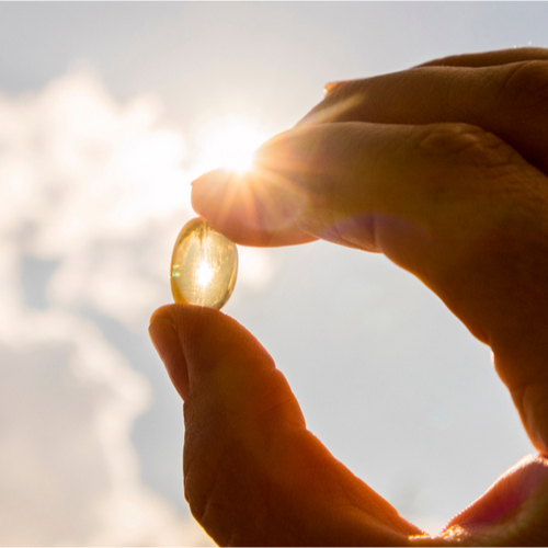Person holding a vitamin D pill.