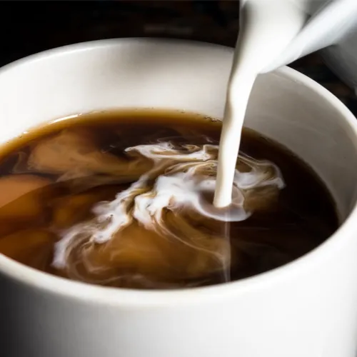 pouring creamer into coffee