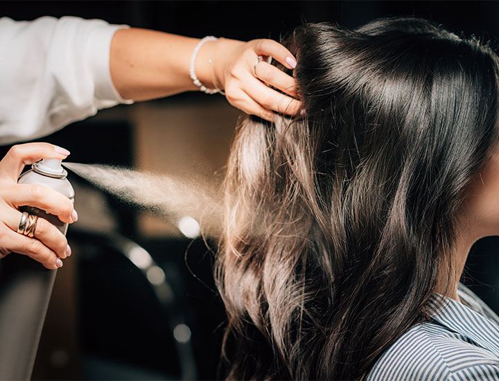 Woman putting dry shampoo on her hair.