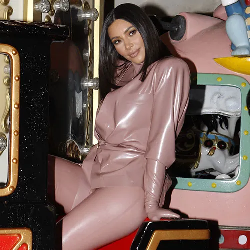 Kim Kardashian posing with a stylish handbag and sunglasses.