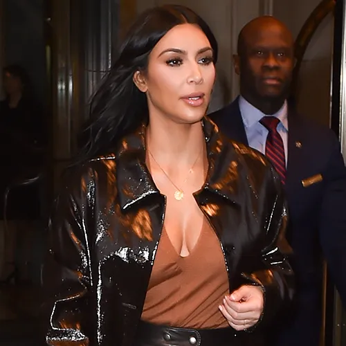 Kim Kardashian smiling in a chic fashion ensemble.