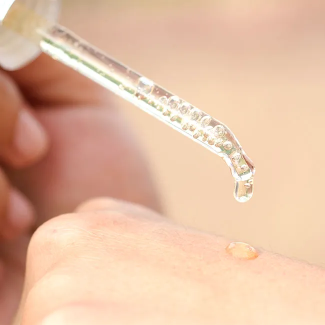 "Dropping vitamin C serum from a dropper bottle"